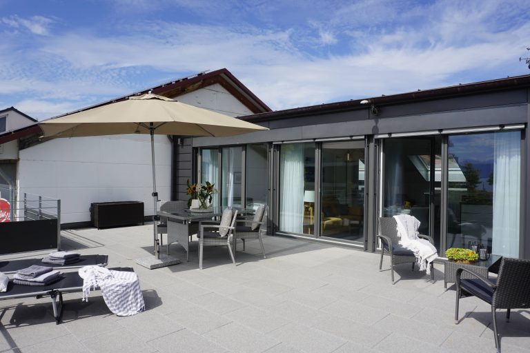 Ferienwohnung, Terrasse mit großem Tisch, Stühlen und Sonnenschirm, Liegestühle