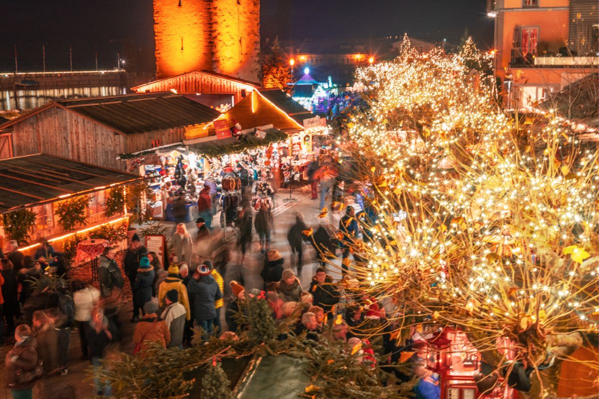 Weihnachtsmarkt am Bodensee 2025: Diese 8 Märkte lohnen sich 8 Lindauer Weihnachtsmarkt am Bodensee bei Abendstimmung mit Lichterketten und Marktständen am Hafen