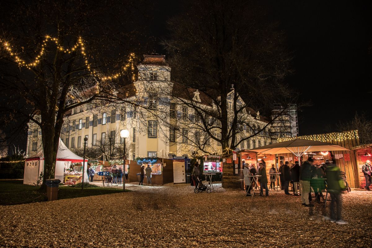 Weihnachtsmarkt am Bodensee 2025: Diese 8 Märkte lohnen sich 2 Weihnachtsmarkt im Hof von Schloss Tettnang bei Abenddämmerung mit Lichtern und geschmückten Buden