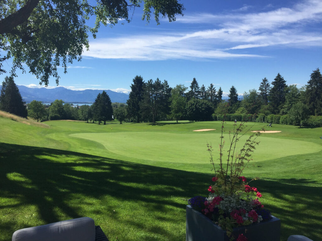 Terrasse des Golfclubs Lindau-Bad Schachen mit Blick auf Golfrasen, Bodensee und Alpen.