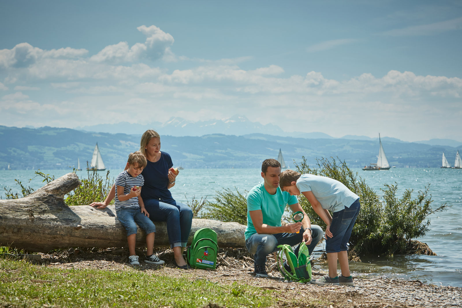 Familie mit Kindern und Forscher-Rucksack am Bodensee an einem sonnigen Tag